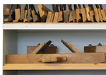 Plane with two irons, working in both directions. On upper shelf: profile planes. Dansk:  Radikalhøvl (nederst) set på nationalmuseets møbelkonserveringsværksted i Brede.