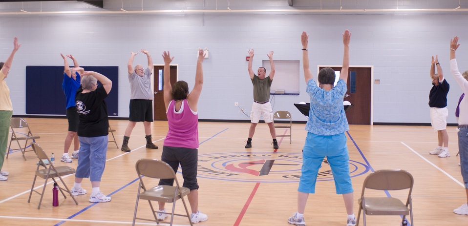 The older individuals pictured here on the wooden floor of an indoor basketball court, were participating in an exercise class consisting of