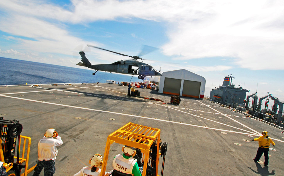 Flight Deck Members Attach Cargo to an MH-60S Knighthawk Helicopter