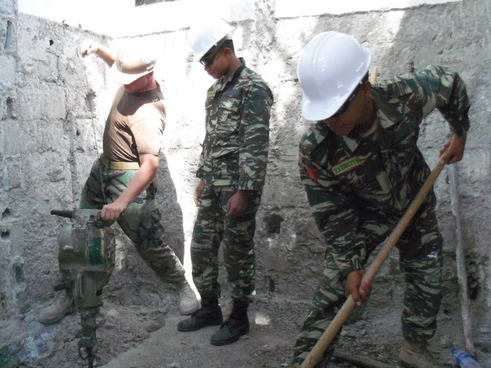 Utilitiesman 2nd Class (SCW) Dines Demonstrates for Timorese Defense Force F-FDTL Workers how To Properly Use a Jack Hammer