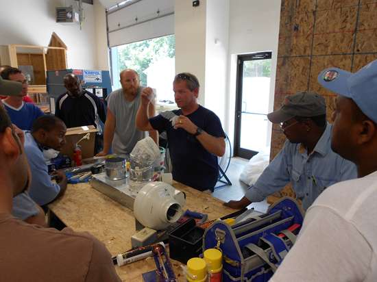 A weatherization trainer instructs a group of students on how to seal a duct as part of the training offered by the Weatherization Assistanc