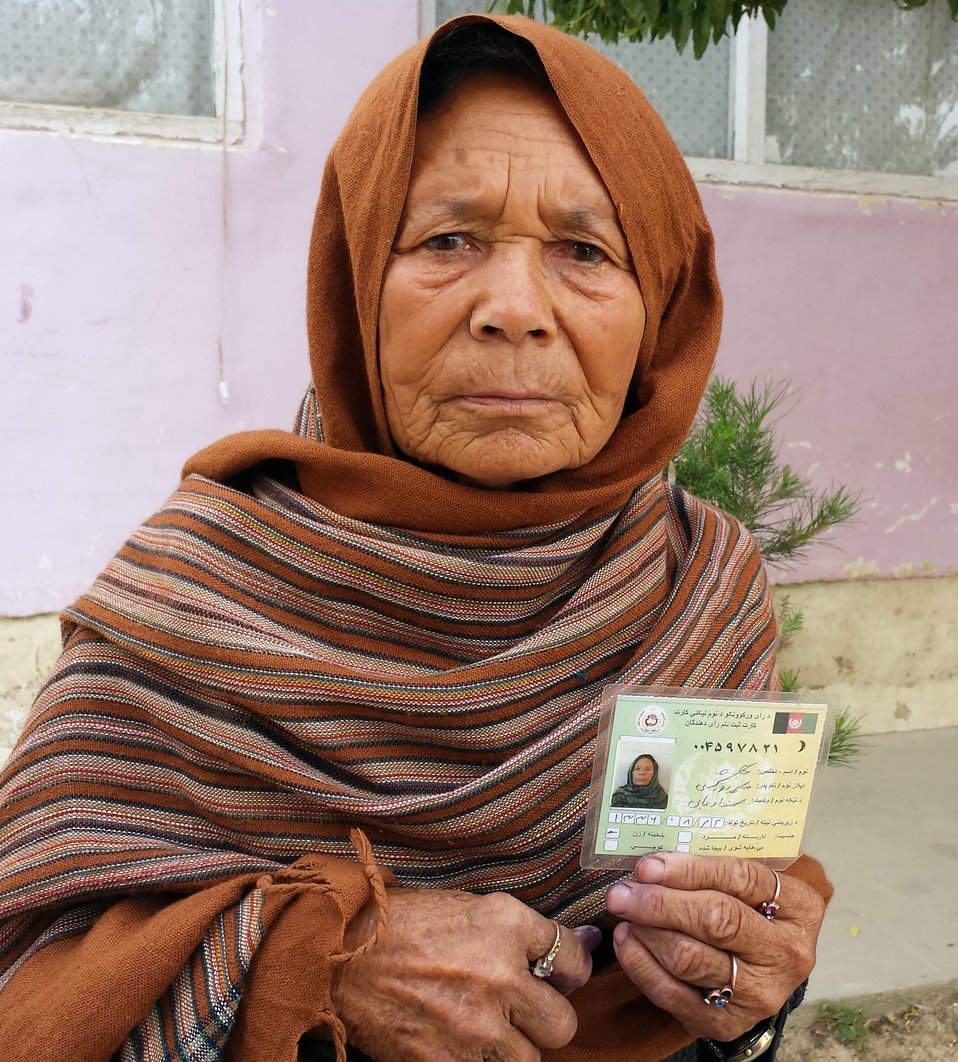 A woman displays her voting card in Samangan province.