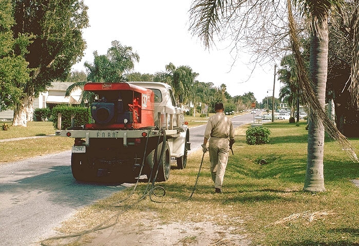 Worker sprays ditch to kill any mosquito larvae that might be present.