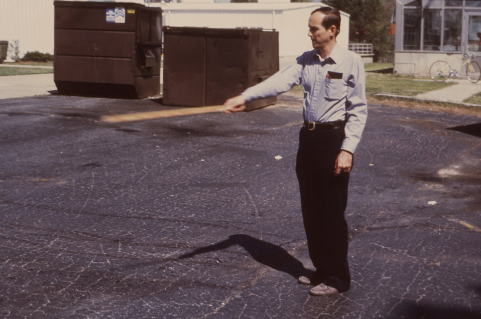 This 1981 photograph depicted a field technician as he swung a yardstick through an insecticide spray in the correct manner used when one is