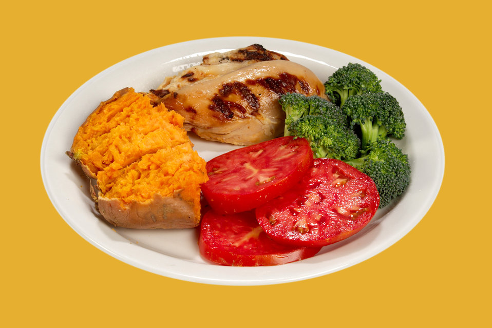 This white ceramic plate had been topped with a healthy, balanced meal consisting of a broiled chicken breast, half a sweet potato, three sl